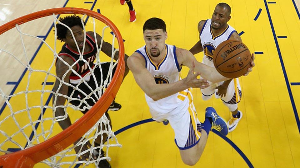 Klay Thompson Golden State Warriors (putih) coba diadang Ed Davis dari Portland Trail Blazers. - INDOSPORT