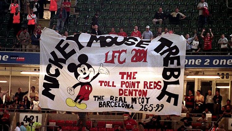Para pendukung Manchester United membentangkan bendera Mickey Mouse Treble. - INDOSPORT