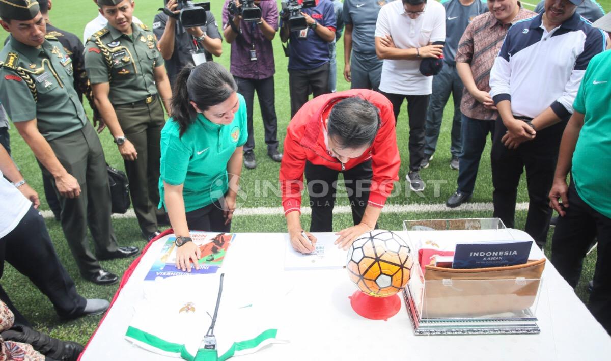 Indosport - Presiden Joko Widodo membubuhkan tanda tangan pada buku Filanesia bersama Ratu Tisha.
