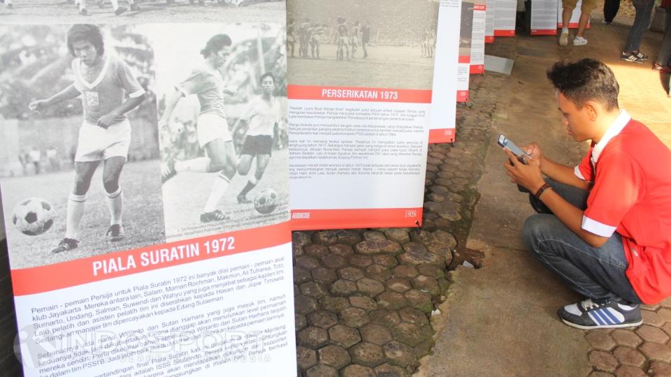 Pengunjung berjongkok di depan banner informasi sejarah kejayaan Persija di masa lalu