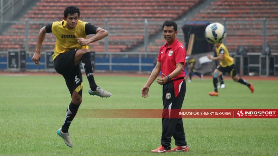 Pemain Mitra Kukar, Rizky Pelu (kiri) melakukan tendangan ke gawang di saksikan pelatih Jafri Sastra (kanan).