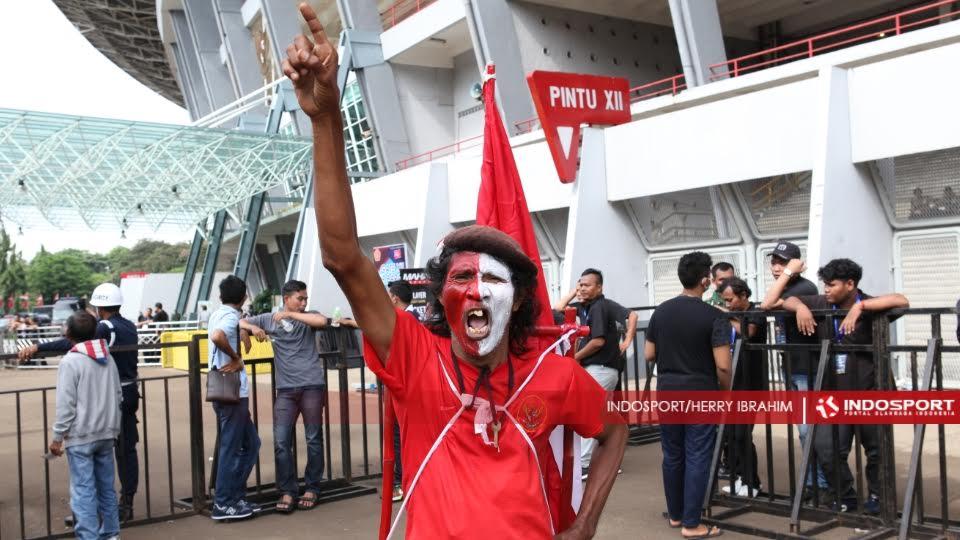 M Kurniawan, mantan atlet maraton Indonesia, dengan atribut timnas Indonesia meramaikan final Piala Jenderal Sudirman antara Semen Padang vs Mitra Kukar di GBK.