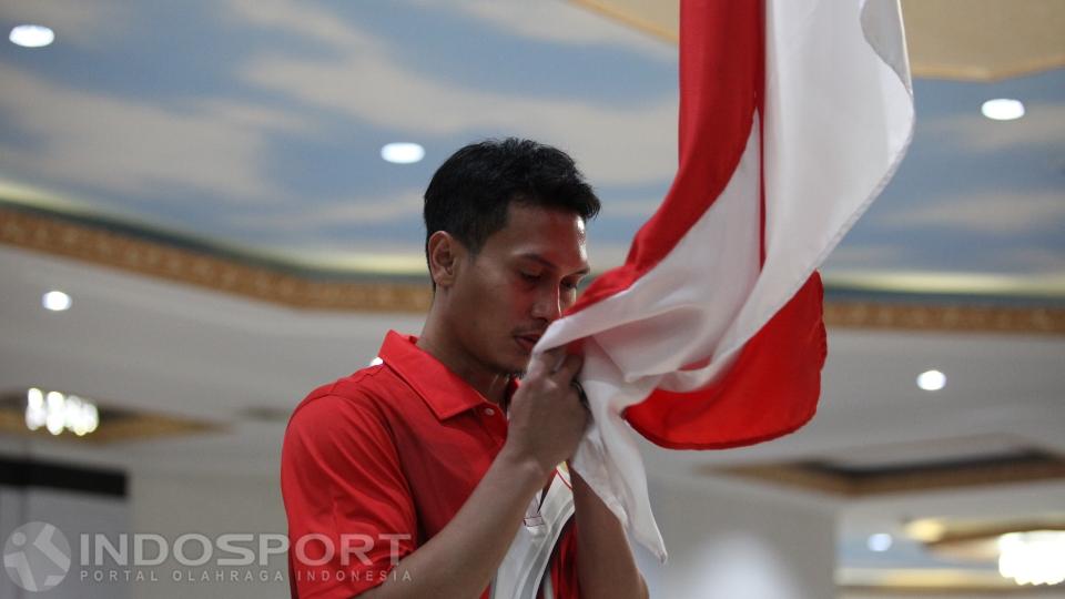 Atlet bulutangkis Mohammad Ahsan mencium bendera Merah Putih pada upacara pengukuhan kontingen Olimpiade 2016 di Wisma Kemenpora, Selasa (21/06/16).