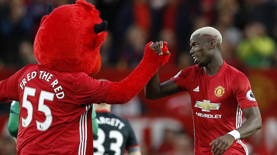 Paul Pogba berjabat tangan dengan maskot Manchester United 