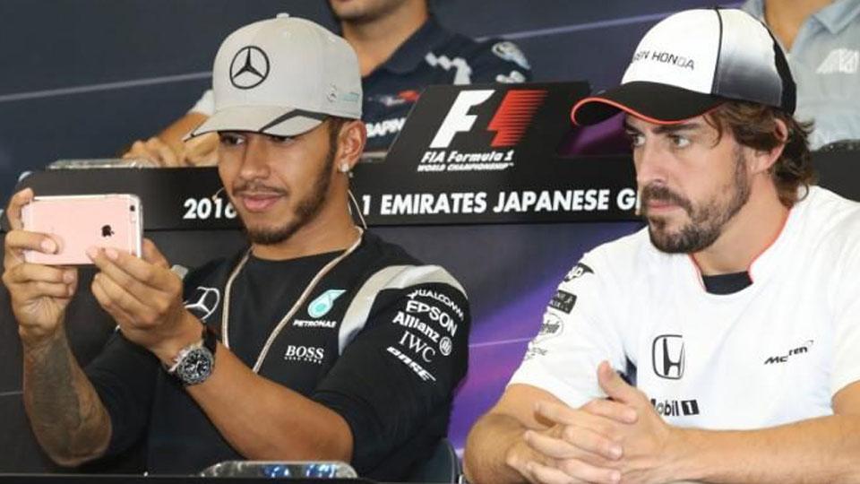 Lewis Hamilton (kiri/Mercedes) lebih memilih bermain Snapchat, sedangkan Fernando Alonso (McLaren-Honda) tetap fokus pada konferensi pers. Copyright: INTERNET