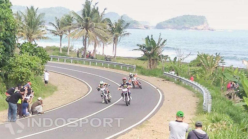 Rider melakukan manuver di tikungan berlatar keindahan Pantai Selatan Malang.