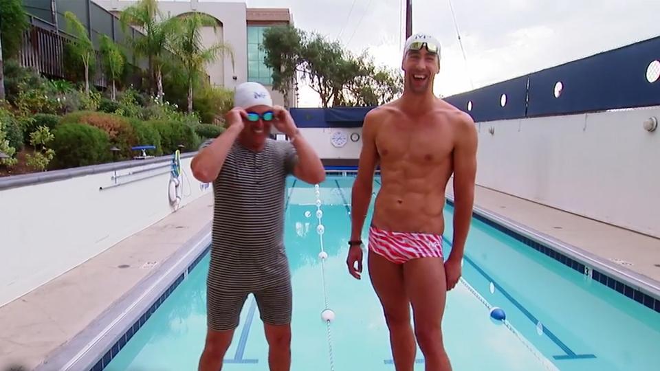 Michael Phelps (kanan) sedang mengajari Andy Lassner berenang. - INDOSPORT