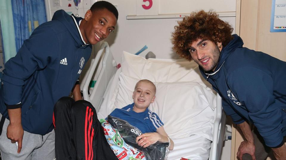 Marouane Fellaini dan Anthony Martial (kiri) memberikan kado Natal untuk seorang anak yang menjadi pasien Rumah Sakit Hospice of St Francis.