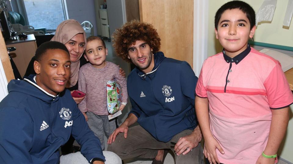 Marouane Fellaini dan Anthony Martial (kiri) memberikan kado Natal untuk seorang anak yang menjadi pasien Rumah Sakit Hospice of St Francis.