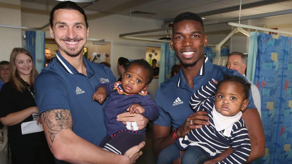 Zlatan Ibrahimovic dan Paul Pogba masing-masing menggendong anak perempuan kecil yang menjadi pasien Rumah Sakit Hospice of St Francis.
