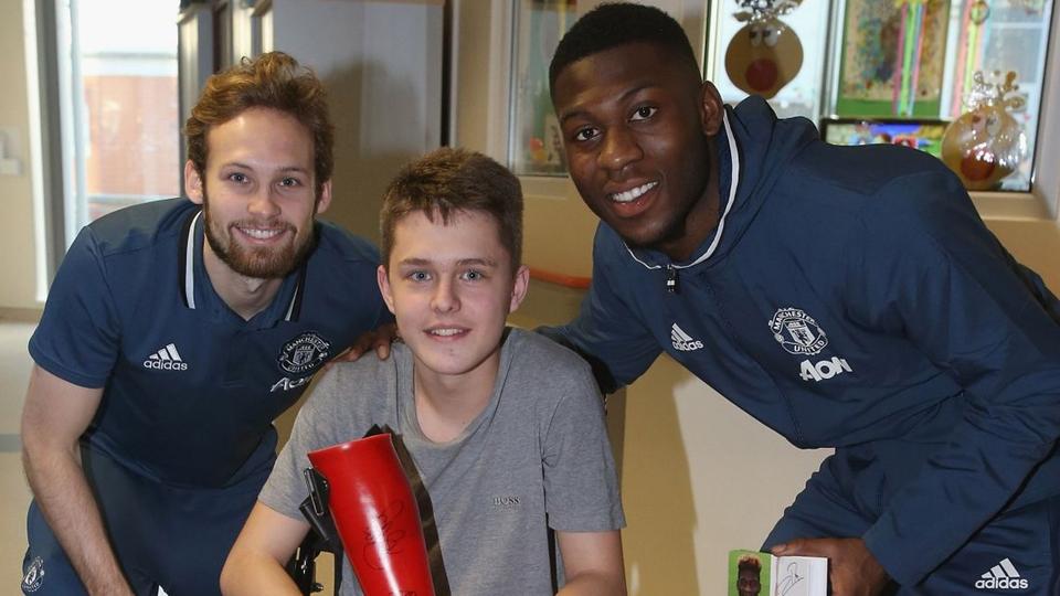 Daley Blind (kiri) dan Timothy Fosu-Mensah memberikan kado Natal untuk seorang anak yang menjadi pasien Rumah Sakit Hospice of St Francis.