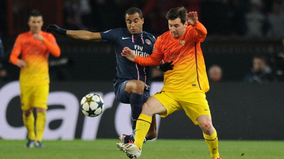 Lucas Moura berusaha menggagalkan aksi Lionel Messi. Copyright: LLUIS GENE/AFP/Getty Images