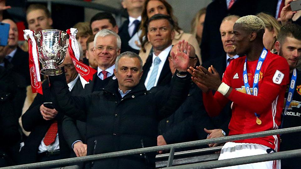 Paul Pogba memberikan trofi Piala Liga Inggris kepada pelatihnya Jose Mourinho.