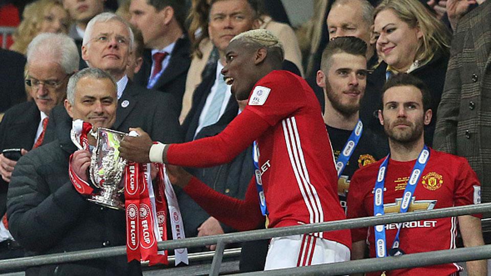 Paul Pogba memberikan trofi Piala Liga Inggris kepada pelatihnya Jose Mourinho.