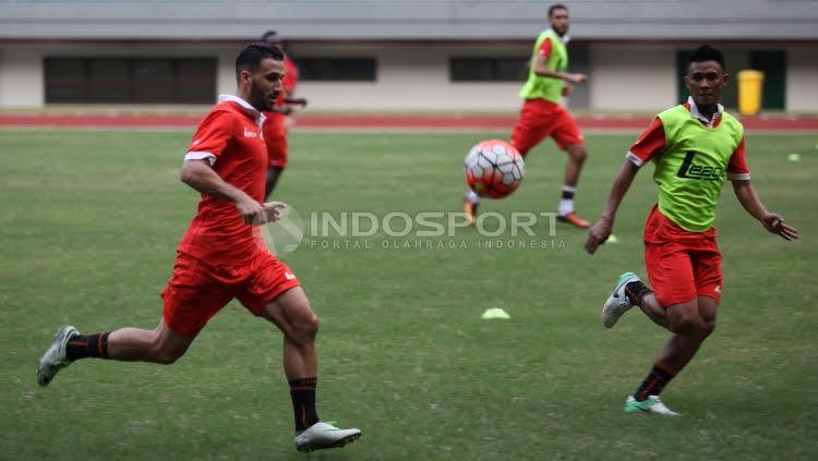 Pemain Persija Jakarta tampak lari kencang untuk mengambila bola dalam sesi latihan.