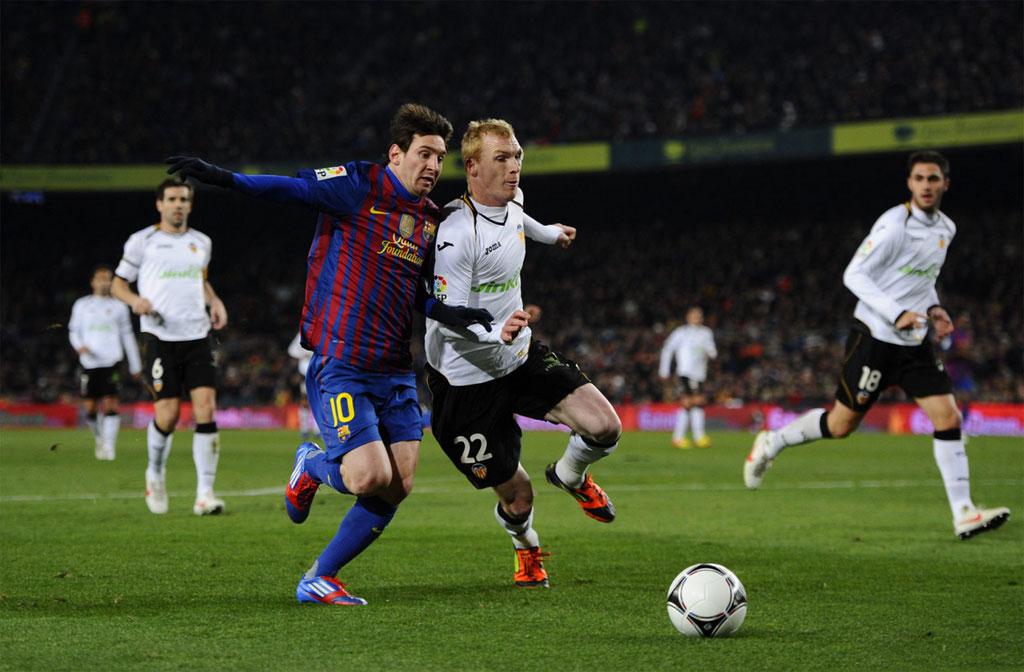 Lionel Messi (kiri) berhadapan dengan Jeremy Mathieu (kanan) saat masih membela Valencia. - INDOSPORT