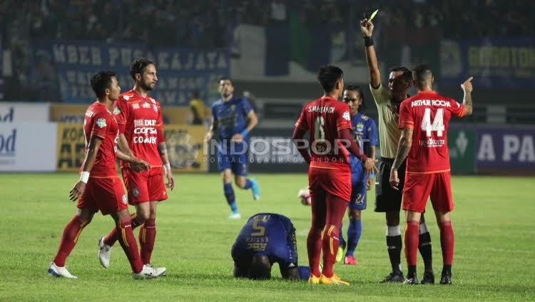 Marquee player Persib Bandung, Michael Essien (tengah) terjatuh usai dilanggar salah satu pemain Arema FC pada laga pembuka Liga 1 di Stadion Gelora Bandung Lautan Api (GBLA), Sabtu (15/04/17).