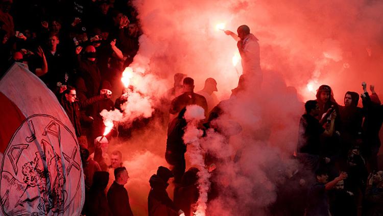 Fans Ajax Amsterdam menyalakan flare di dalam stadion. Copyright: OLAF KRAAK/AFP/Getty Images