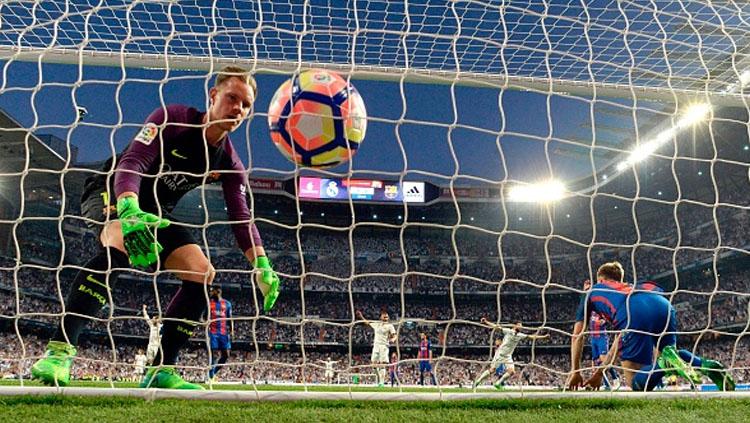 Kiper Barcelona, Marc-Andre Ter Stegen mengambil bola setelah gawangnya dibobol Casemiro sebagai gol pembuka untuk Madrid. Copyright: GERARD JULIEN/AFP/Getty Images