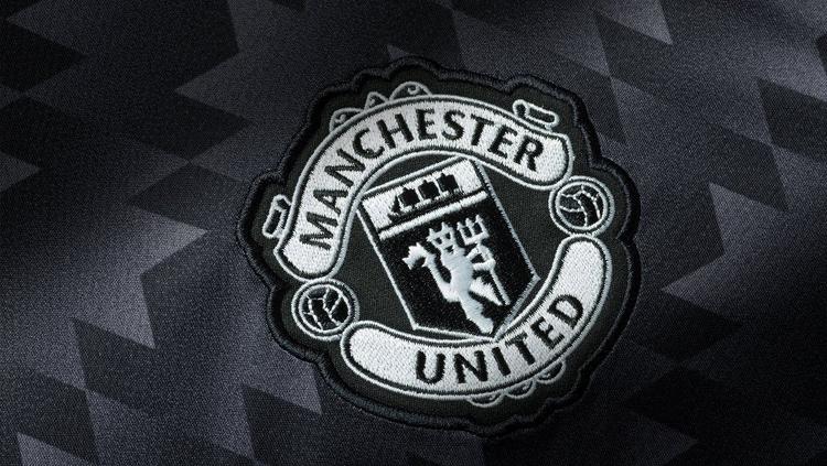 Logo Manchester United dengan background jersey tandang mereka musim depan. - INDOSPORT