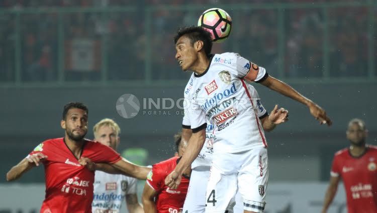 Kapten Bali United, Fadil Sausu (tengah) mengahalau bola yang mengarah ke gawang Bali United dengan sundulan.