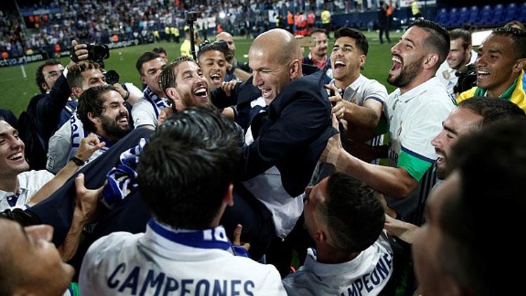Zinedine Zidane tengah diangkat anak asuhnya untuk merayakan kemenangan mereka setelah laga penentuan melawan Malaga. Copyright: Burak Akbulut/Anadolu Agency/Getty Images