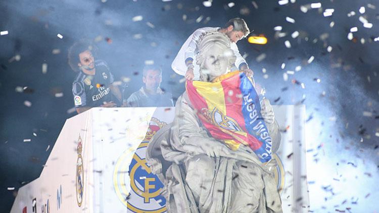 Sergio Ramos tengah memakaikan bendera Spanyol pada patung dewa Cibeles saat jalani parade di alun-alun Cibeles, Spanyol.