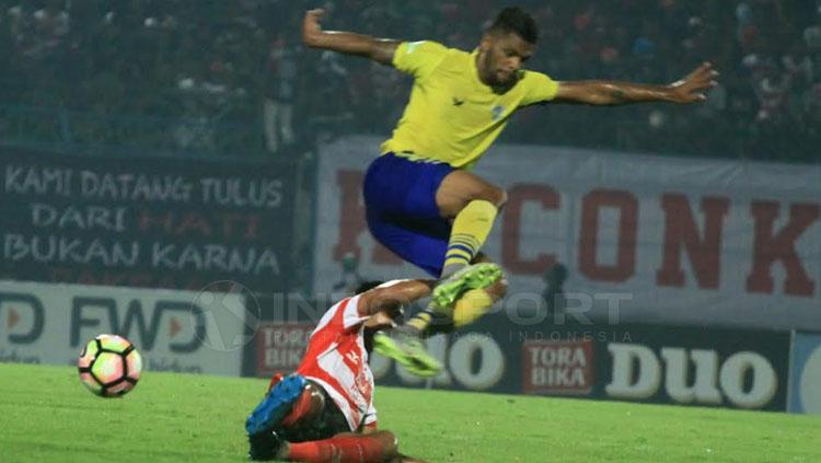 Lompatan tinggi Patrick Da Silva, menghindari tekling pemain Madura United.