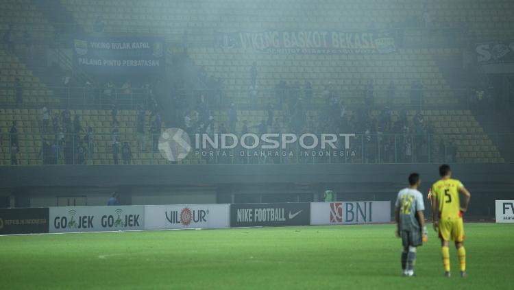 Dua pemain Bhayangkara FC menyaksikan tindakan pendukung Persib Bandung, Bobotoh masuk ke dalam lapangan.