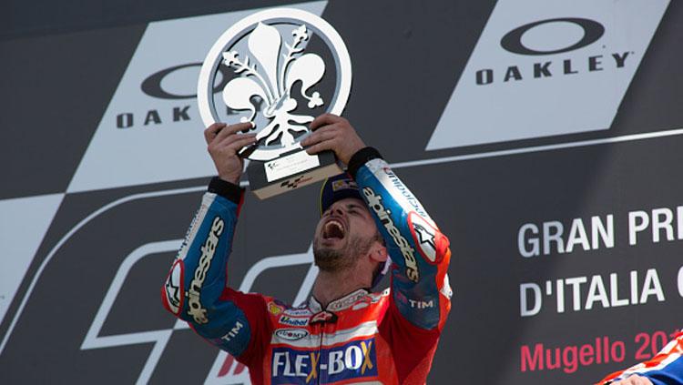 Aksi selebrasi Andrea Dovizioso atas podium bersama trofi MotoGP Italia. Copyright: INDOSPORT