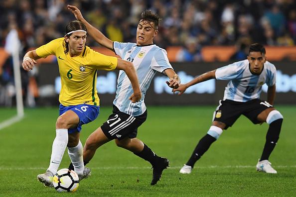 Paulo Dybala (tengah) ketika berduel dengan Filipe Luis. Copyright: Getty Images