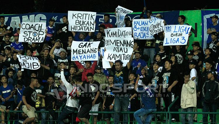 Aremania di tribun selatan menunjukkan berbagai poster kritikan kepada Aji Santoso Copyright: Indosport/Ian Setiawan