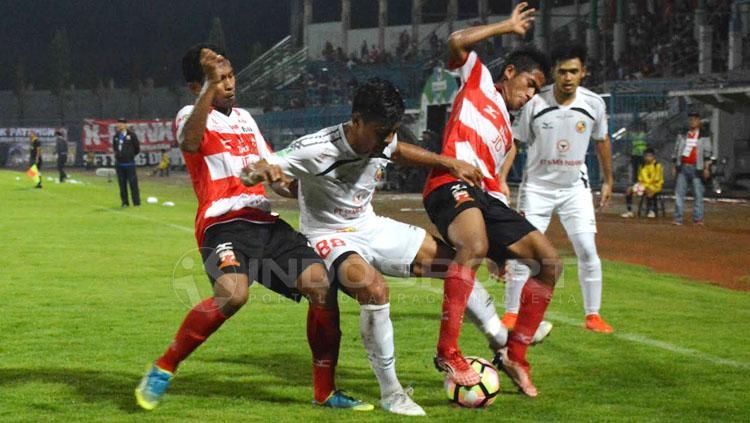 Salah satu pemain Semen Padang mendapat kawalan ketat dari pemain Madura United.