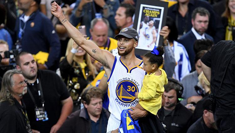 Stephen Curry menggendong anaknya, Riley Curry saat merayakan kemenangan Golden State Warriors.