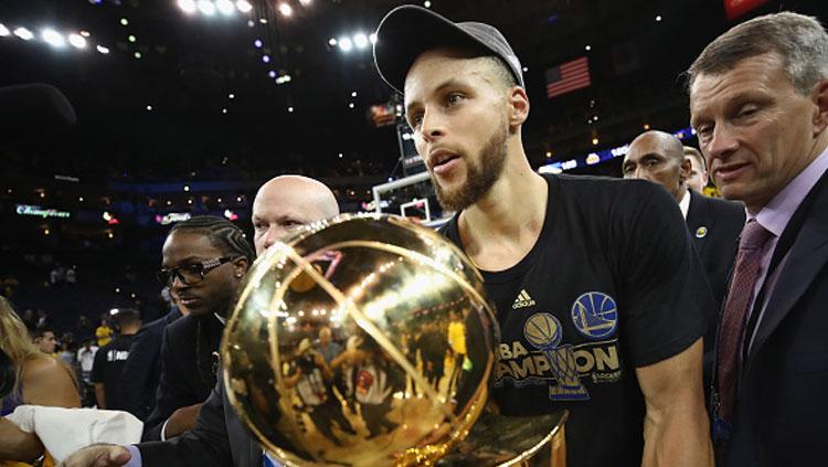 Stephen Curry membawa trofi NBA setalah timnya berhasil menang melawan Cleveland Cavaliers.