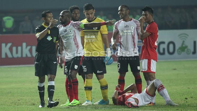 Seorang pemain Persija Jakarta terkapar di atas tanah.