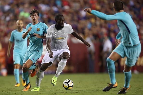 Romelu Lukaku tengah mencoba melepaskan diri dari pengawalan ketat pemain Barcelona. Copyright: Robbie Jay Barratt - AMA/Getty Images