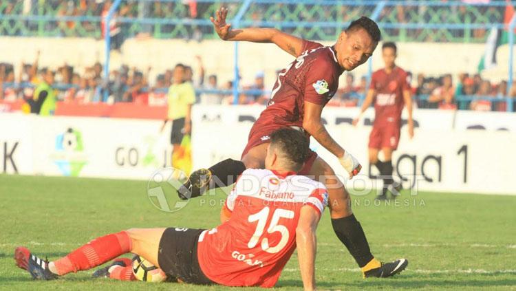 Ferdinand Sinaga sampai terjengkang setelah bola berhasil disapu bersih Fabiano Beltrame. FOTO: Ian Setiawan/Soicaumienbac.cc