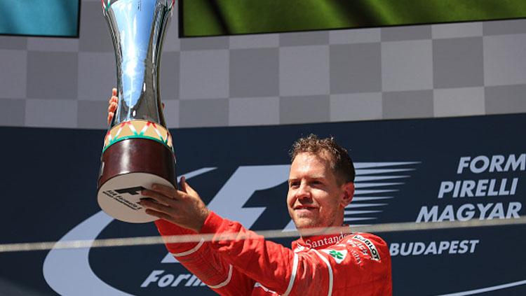 Sebastian Vettel menunjukan trofi diatas podium.