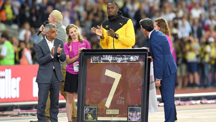 Usain Bolt menerima potongan trek Olimpiade London 2012 dari Gubernur London, Sadiq Khan (jas abu-abu). Copyright: INDOSPORT