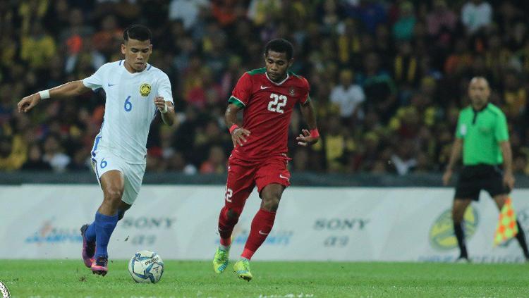 Yabes Roni Malaifani dampingi pemain Malaysia saat menggiring bola. Copyright: twitter@FAM_Malaysia