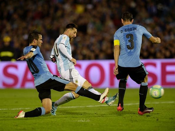 Pemain megabintang Argentina, Lionel Messi (tengah) dikepung oleh 2 pemain Uruguay, Alvaro Gonzales (kiri) dan Diego Godin. Copyright: INDOSPORT