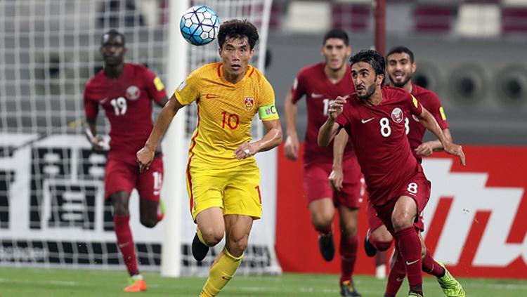 Zheng Zhi (China kaos kuning) berusaha lari untuk mendapatkan bola dari pemain Qatar. Copyright: in
