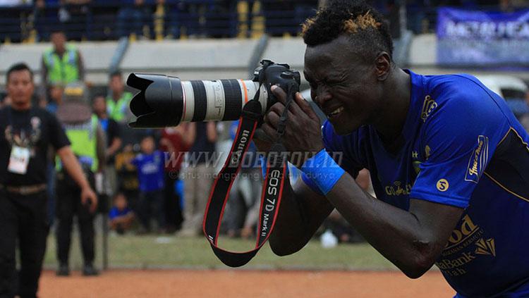 Selebrasi membidik kamera yang dilakukan Ezechiel N’Douassel usai mencetak gol ke gawang Semen Padang. Copyright: Bobotoh.id