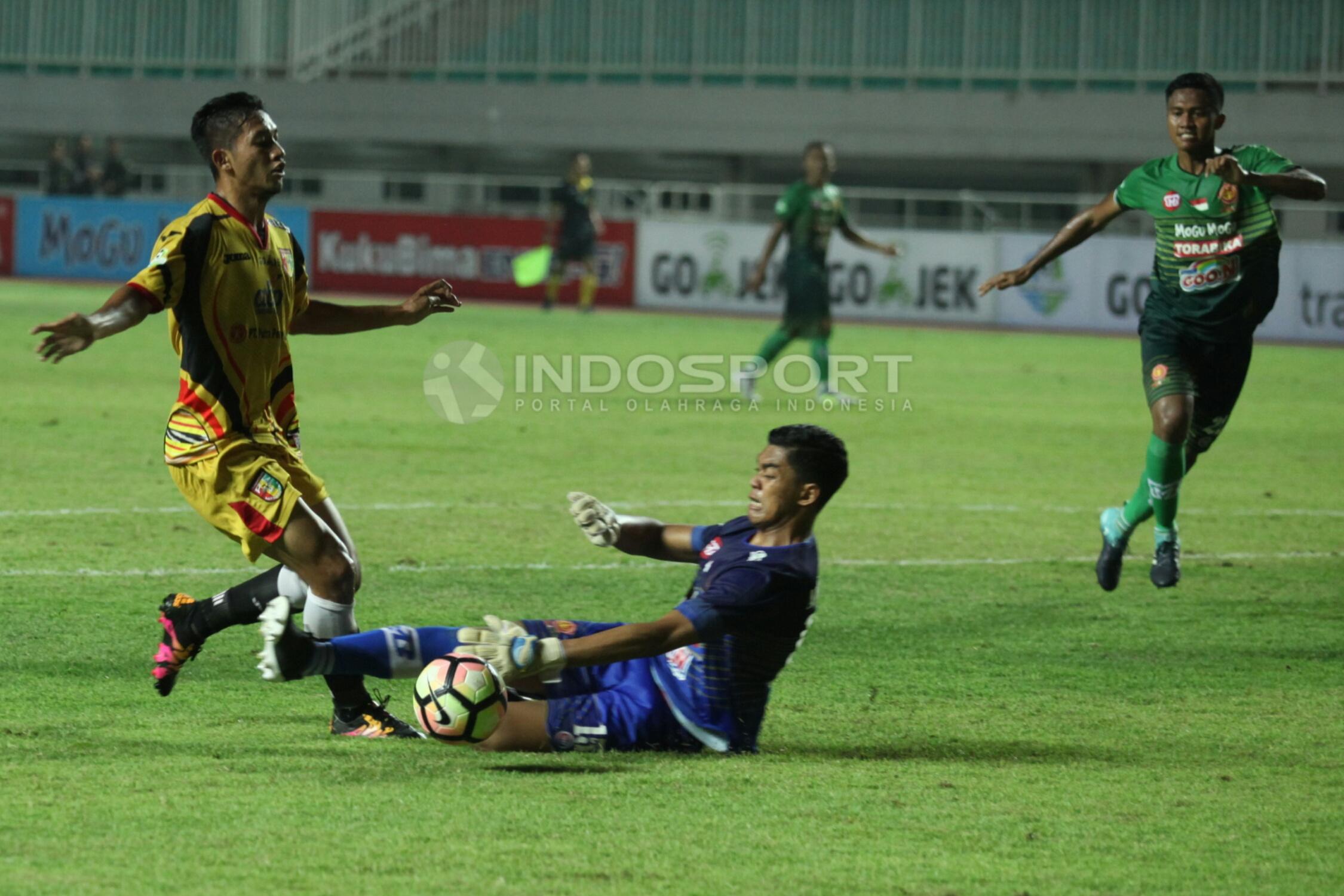 Kiper PS TNI, Teguh Amiruddin (tengah) melanggar pergerakan pemain Mitra Kukar, Anindito Wahyu di kotak terlarang.