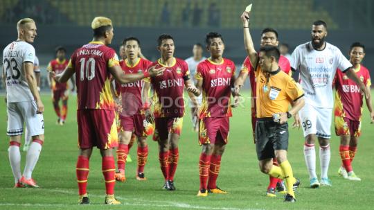 Wasit Rysbek Shekerbekov (kanan) memberikan kartu kuning kepada Jajang Mulyana (kiri).