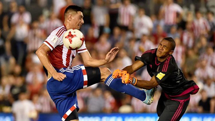 Pemain Paraguay Oscar Cardozo (kiri) berebut bola dengan kiper Venezuela, Wuilker Farinez. Copyright: INDOSPORT