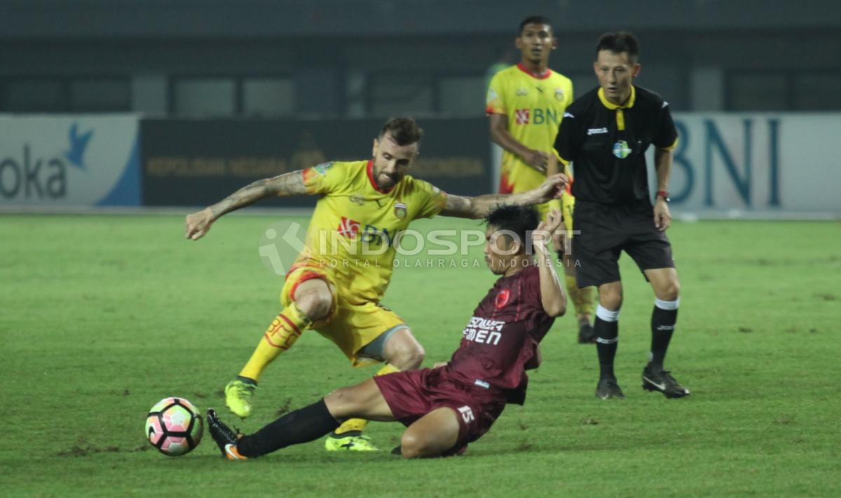 Pemain PSM Makassar, Arfan (bawah) melakukan tackle kepada pemain Bhayangkara FC, Paulo Sergio Moreira.