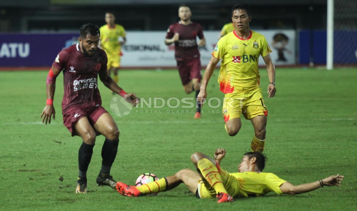 Pemain PSM Makassar, Marc Anthony Klok (bawah) melakukan pelanggaran kepada striker BFC, Guy Junior.