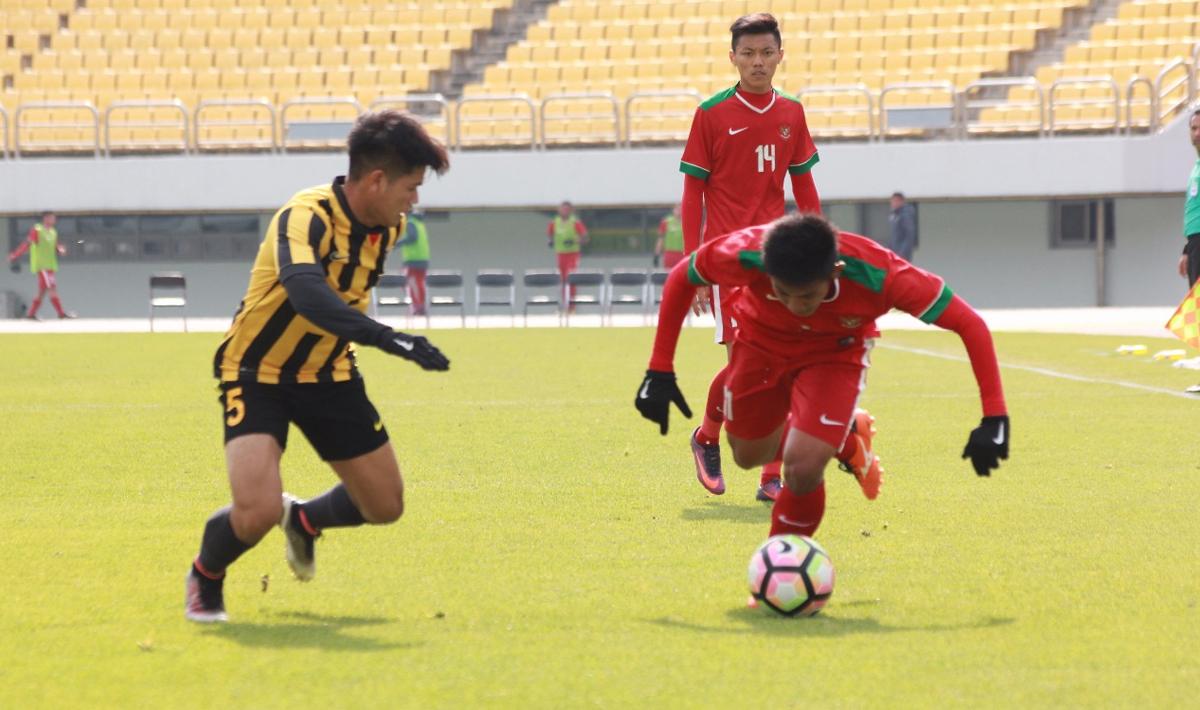 Pemain Garuda Nusantara tengah mengontrol bola dari pemain Malaysia.